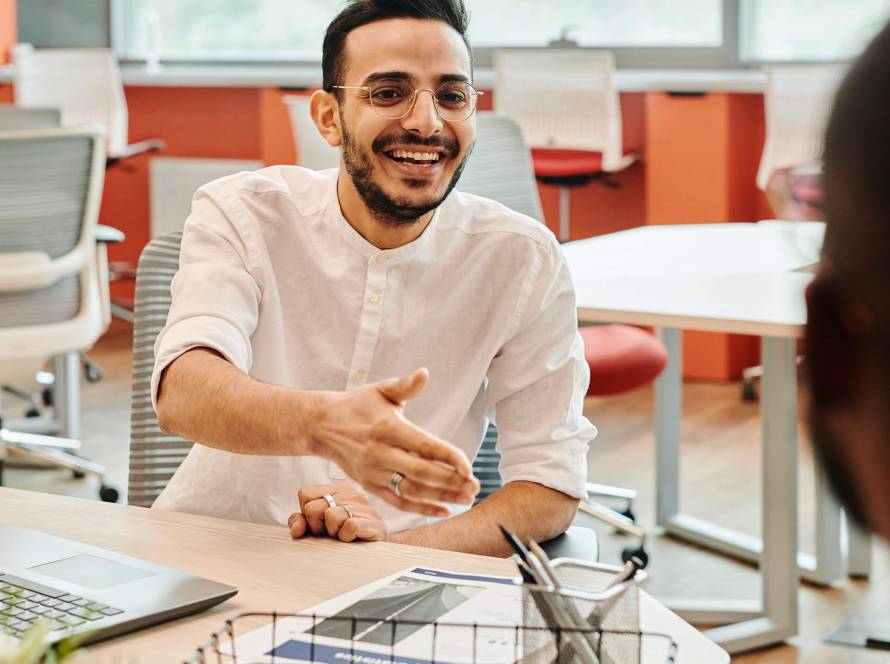 Smiling man offering handshake at meeting.